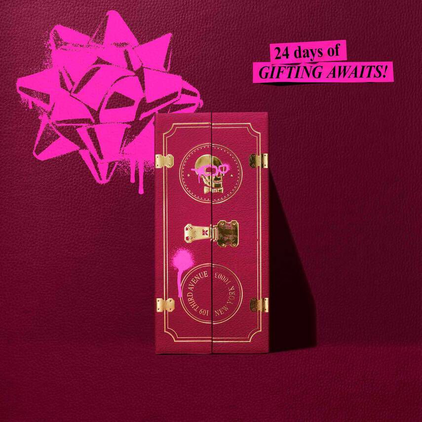 A deep burgundy Kiehl’s Advent Calendar box is featured closed against a matching textured background. The gold foil text on thebox reads “SHARING JOY SINCE 1851" with “ADVENT CALENDAR" at the bottom. A bright pink graffiti-style bow is illustrated above the box,and a pink banner in the top right corner reads: “24 days of GIFTING AWAITS!"