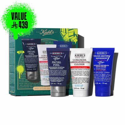 A graphic, set against a dark green textured background, features three Kiehl’s products. A white tube of "KIEHL’S ULTRA FACIAL BARRIER-HYDRATING CLEANSER" is labeled "TRAVEL SIZE" in bright green. A blue tube of "KIEHL’S 'CLOSE-SHAVERS' SQUADRON ULTIMATE BRUSHLESS SHAVE CREAM" is also labeled "TRAVEL SIZE" in bright green. A dark blue tube of "KIEHL’S FACIAL FUEL MOISTURIZER" is labeled "TRAVEL SIZE" in bright green. In the lower right, a partially visible green Kiehl’s gift box showcases the same three products.