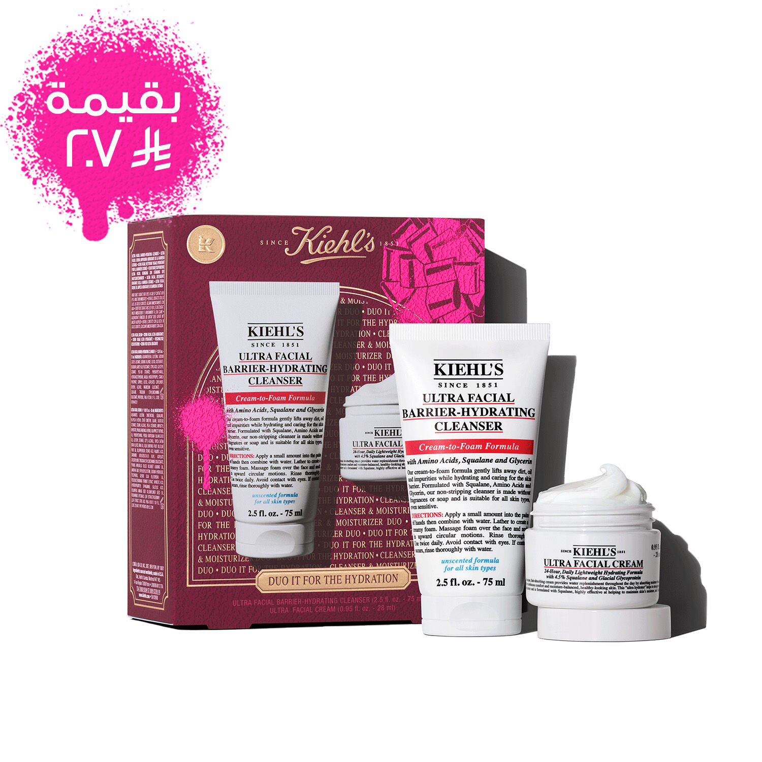 A graphic displays a Kiehl's gift set box, primarily in dark red, featuring a pink bow graphic in the upper right and a pink paint splatter in the lower left. The box states "DUO IT FOR THE HYDRATION" on its front, along with "ULTRA FACIAL BARRIER-HYDRATING CLENSER + ULTRA FACIAL CREAM. To the right of the box, the two products are shown outside their packaging.