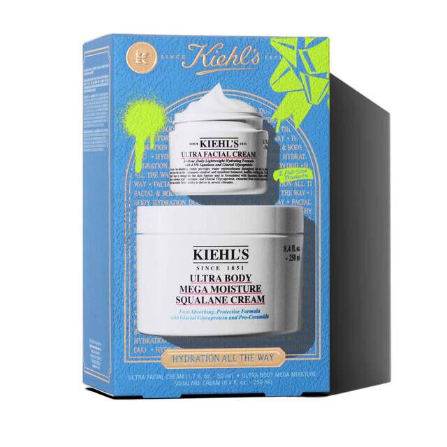 A graphic featuring a blue Kiehl’s gift box. The box contains two white jars: "KIEHL’S ULTRA FACIAL CREAM" and "KIEHL’S ULTRA BODY MEGA MOISTURE SQUALANE CREAM." The box has bright green graphic paint splatters and a bow design, and features the text "HYDRATION ALL THE WAY" on the front.