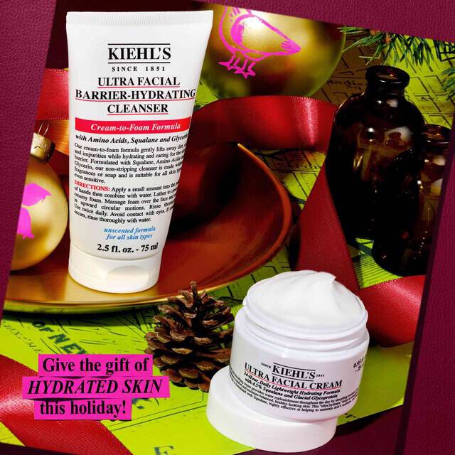 A festive graphic showing a white tube of Kiehl’s Ultra Facial Barrier-Hydrating Cleanser and a white jar of Kiehl’s Ultra Facial Cream, set against a background of red ribbon and green wrapping paper with golden ornaments. Prominently displayed text reads: "Give the gift of HYDRATED SKIN this holiday!".